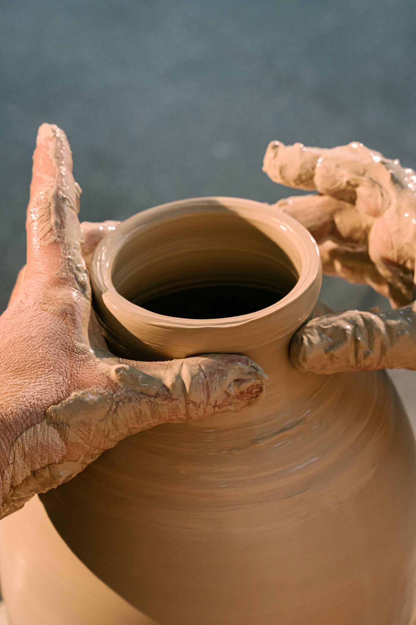 Stock photograph of hands working clay at a pottery wheel.